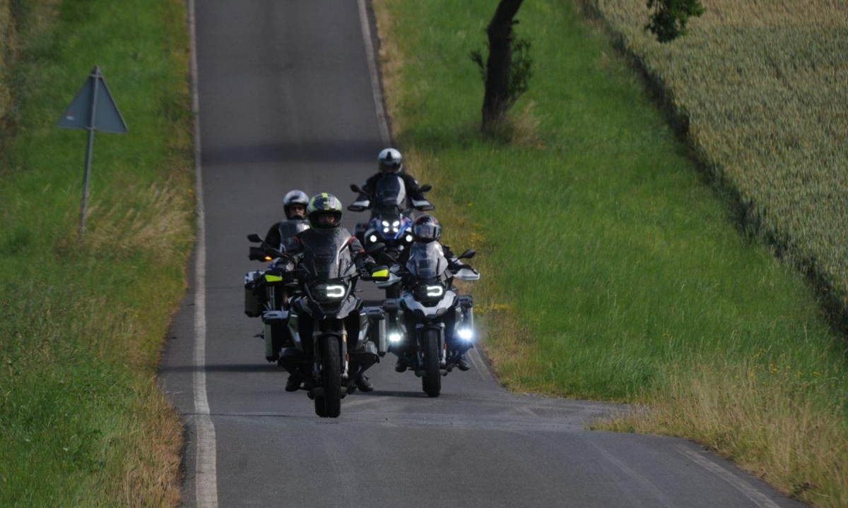Vier Motorradfahrer fahren in einer Gruppe eine schmale Teerstrasse entlang