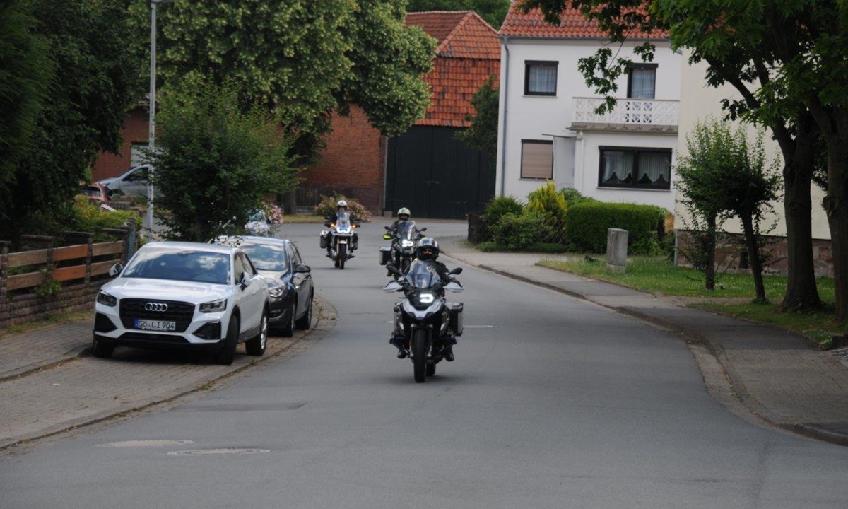 mehrere Motorradfahrer fahren auf einer Strasse durch eine Ortschaft