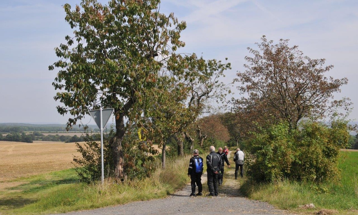 Eine Gruppe von Personen in Motorradkleidung steht auf einem Feldweg