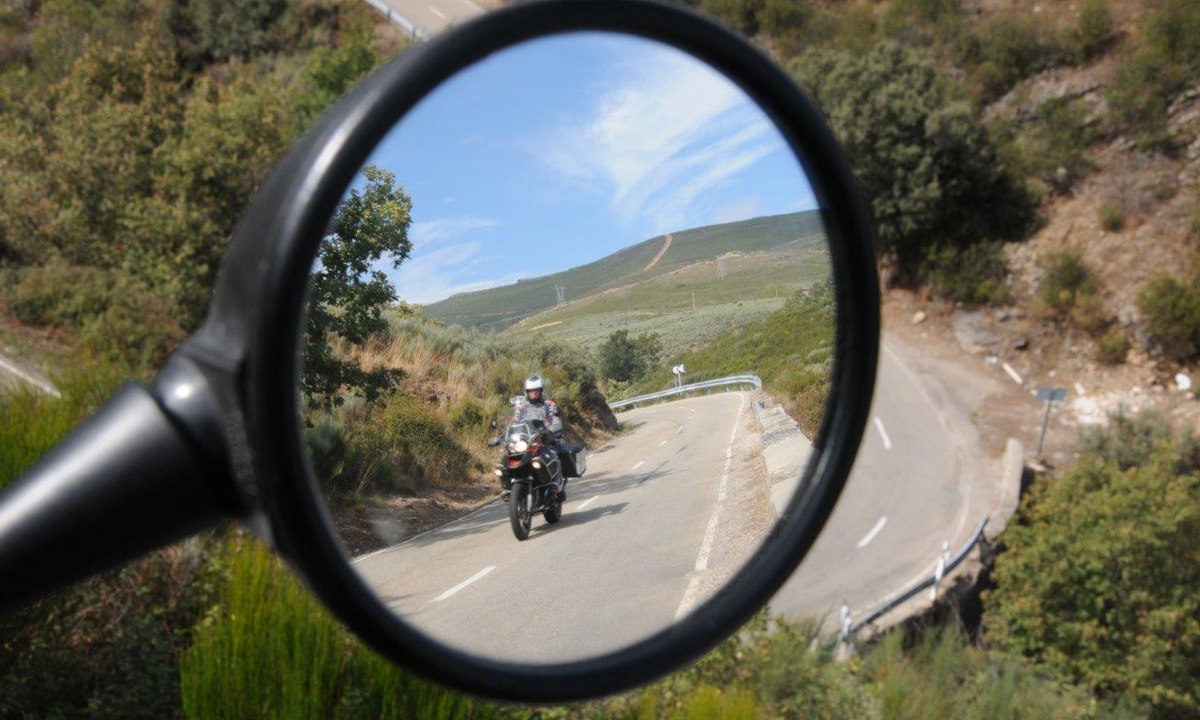 Blick auf einen anderen Motorradfahrer in Rueckspiegel des Motorrads