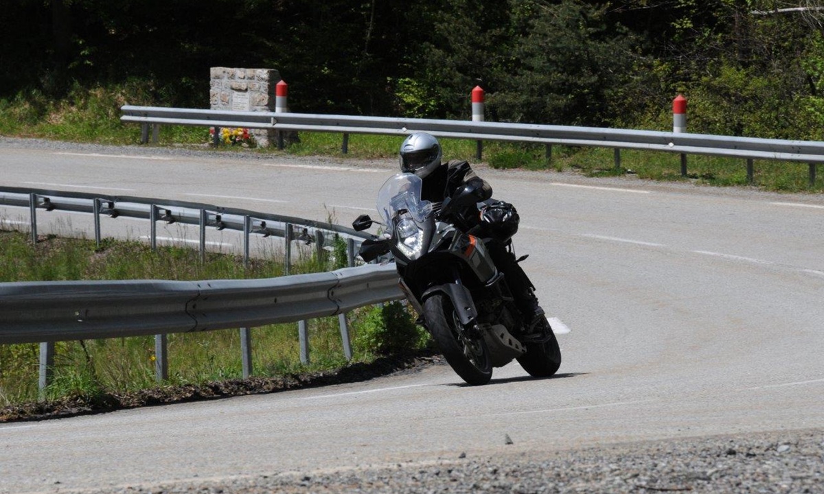 ein schwarz gekleideter Motorradfahrer neigt sich mit seinem Bike in die Kurve einer Landstrasse