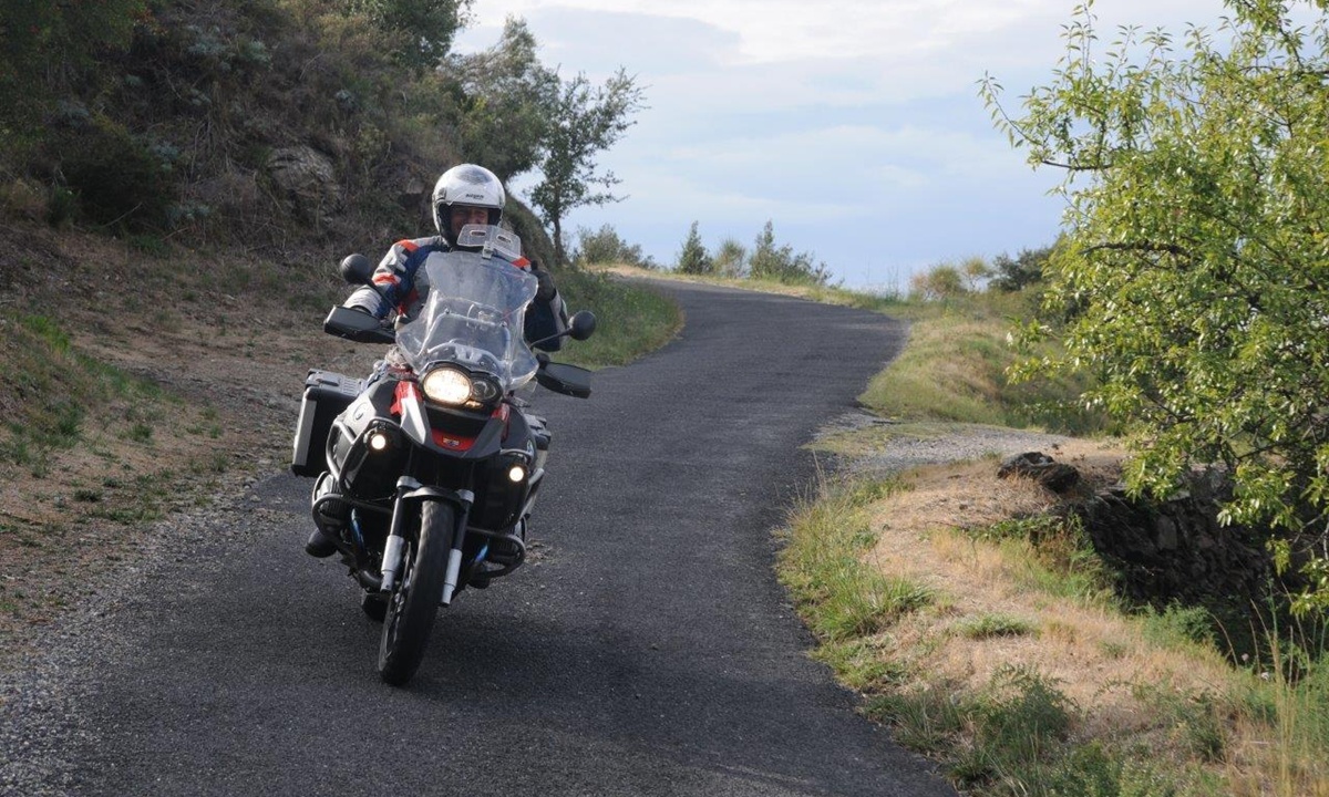 Ein Motorradfahrer auf einer schmalen geteerten Bergstrasse in den Alpen