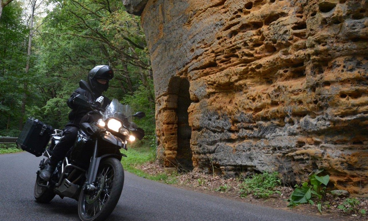 ein Motorrad faehrt neben einer steinernen Steilwand entlang