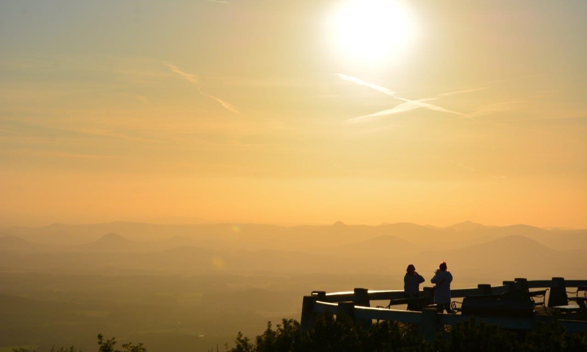 Silhuetten zweier Personen auf einer Aussichtsplattform im Sonnenuntergang