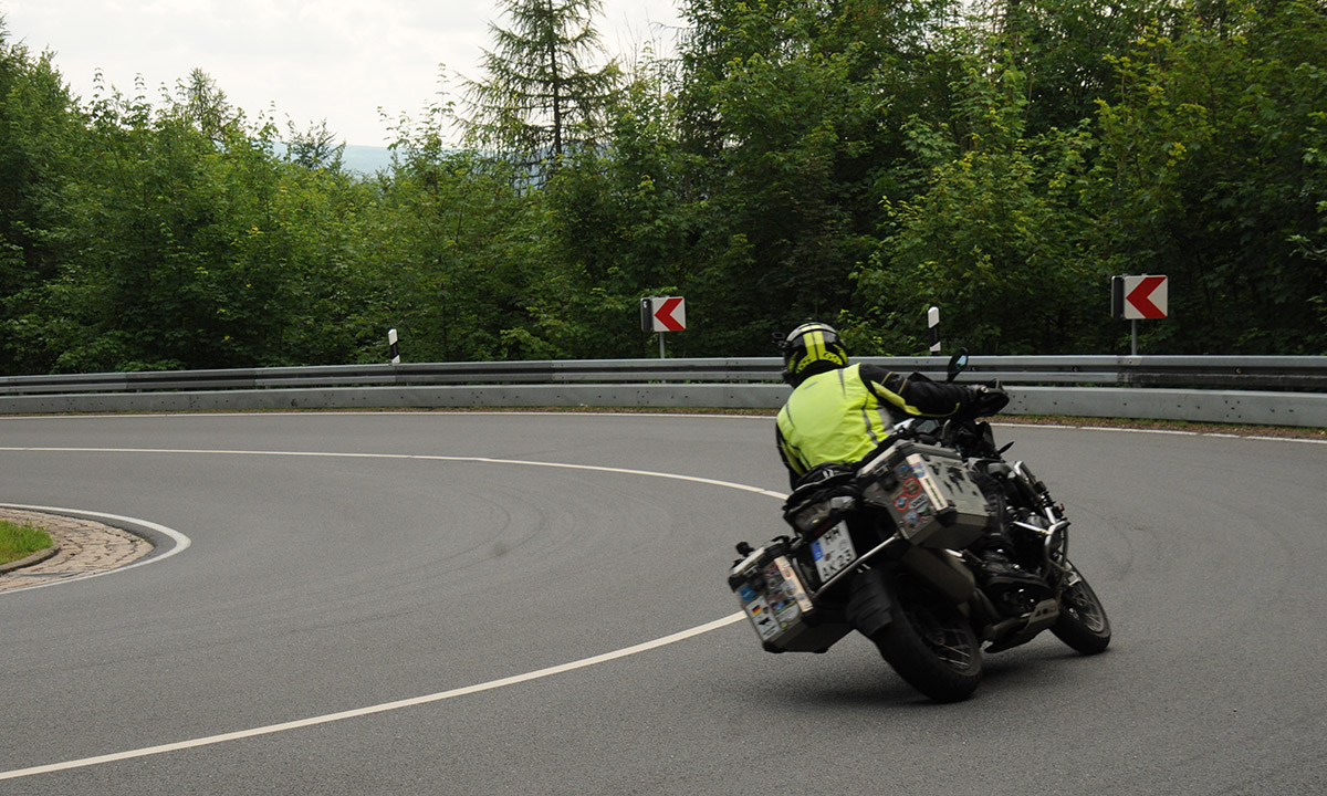 ein mit Koffern bestuecktes Motorrad neigt sich in die Kurve einer Landstrasse
