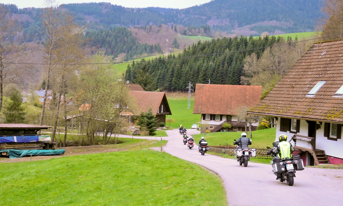 sechs Motorraeder fahren hintereinander druch ein kleines indyllisches Dorf im Schwarzwald