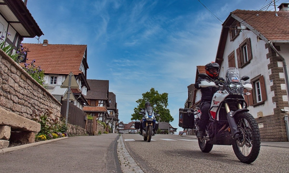 zwei Motorraeder durchfahren ein kleines Dorf mit zahlreichen Fachwerkhaeusern
