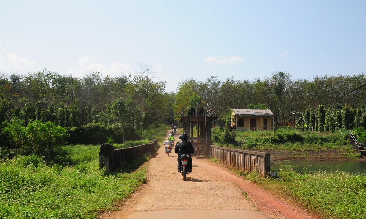 Ein Motorrad ueberquert eine Bruecke ueber einem Fluss in einem laendlichen Gebiet Vietnam