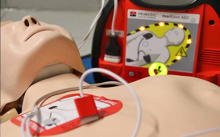 Detailaufnahme einer Reanimationspuppe mit auf die Brus geklepter Elektrode eines Defibrillators