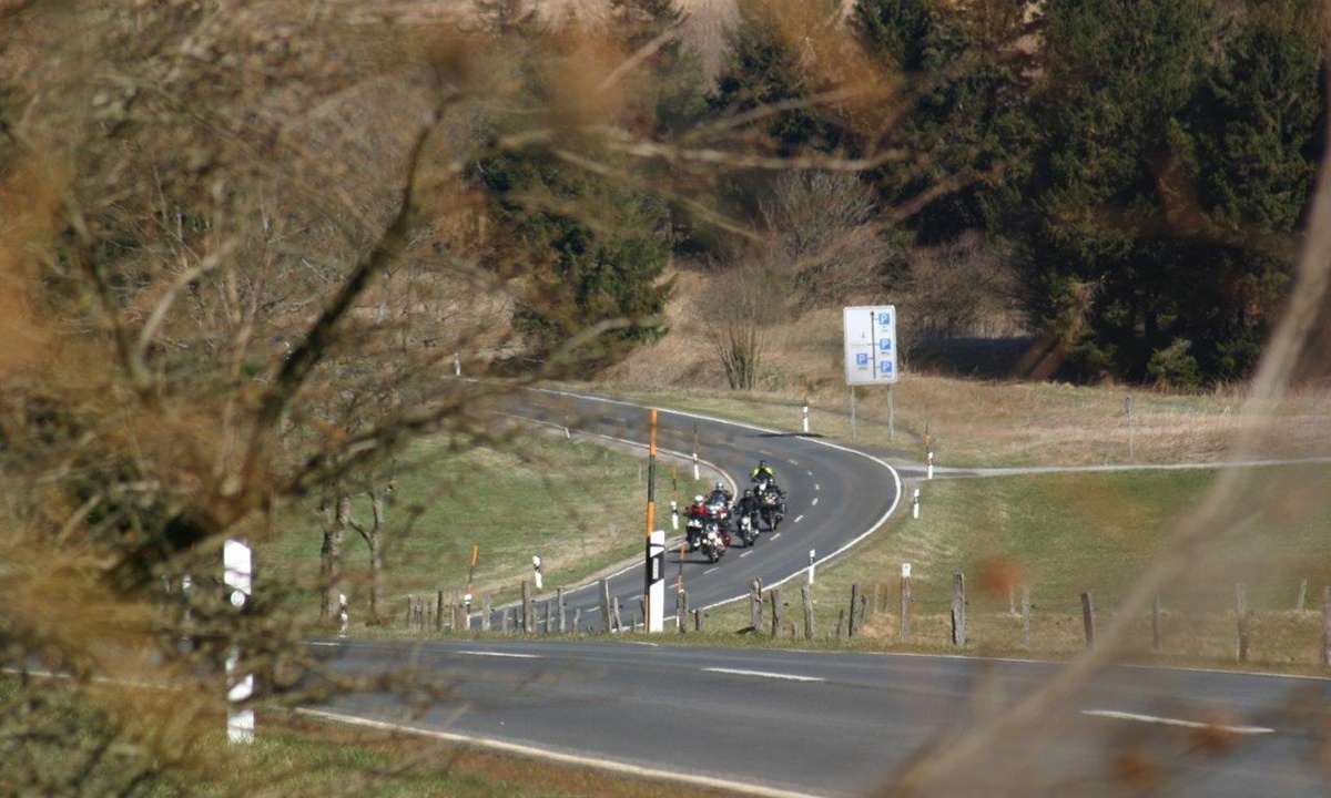 eine Gruppe Motorradfahrer faehrt gemeinsam auf einer kurvigen Landstrasse