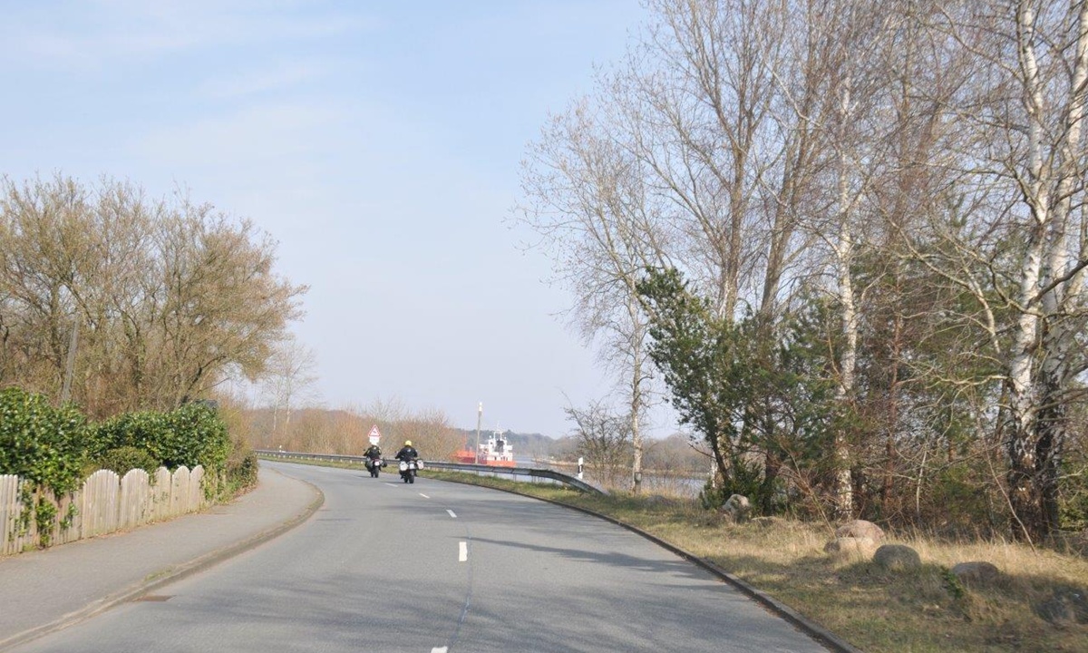 Zwei Motorradfahrer fahren auf einer Strasse entlang des Nord-Ostsee-Kanals in Schleswig-Holstein