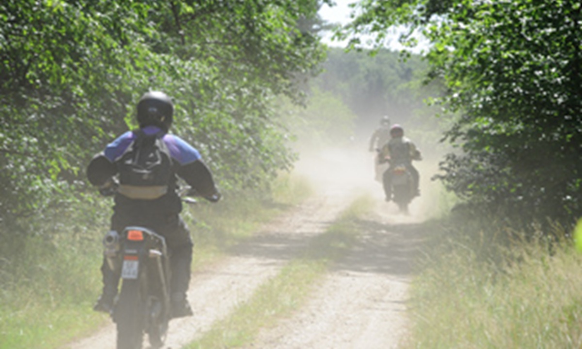 Motorradfahrer auf einem staubigen Feldweg