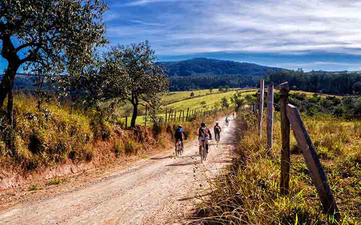 Eine Gruppe Mountainbiker faehrt auf einem abgelegenen Feldweg durch eine bergige Landschaft