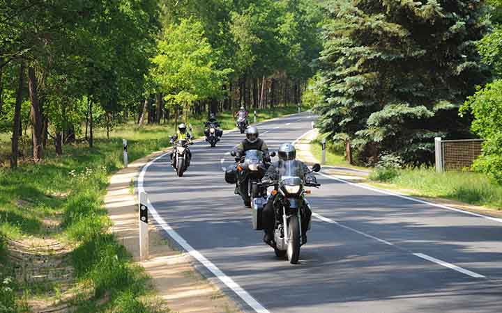 eine Gruppe Motorradfahrer faehrt eine Landstrasse entlang 