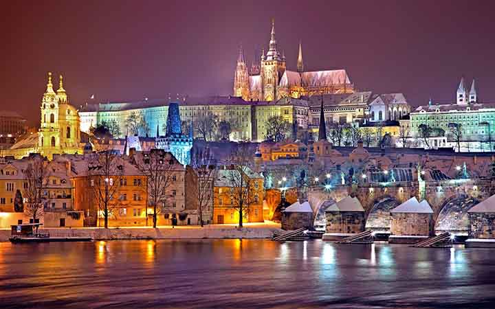 naechtlicher Blick ueber die Moldau auf die beleuchtete Altstadt von Prag