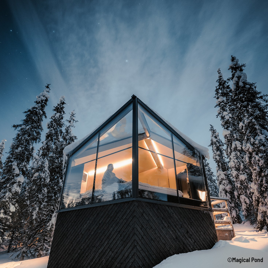 Glaesernes Bungalow bei Nacht in der verschneiten Winderlandschaft Lapplands